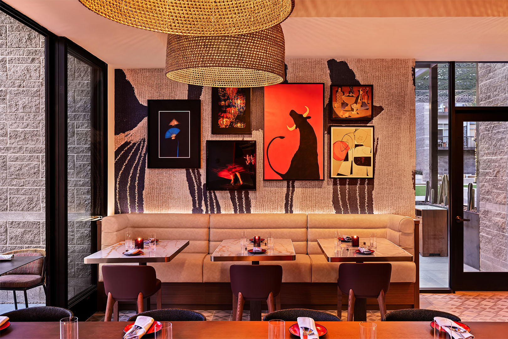 Intimate booth seating area with artistic wallpaper and a bold gallery wall featuring a red bull silhouette.